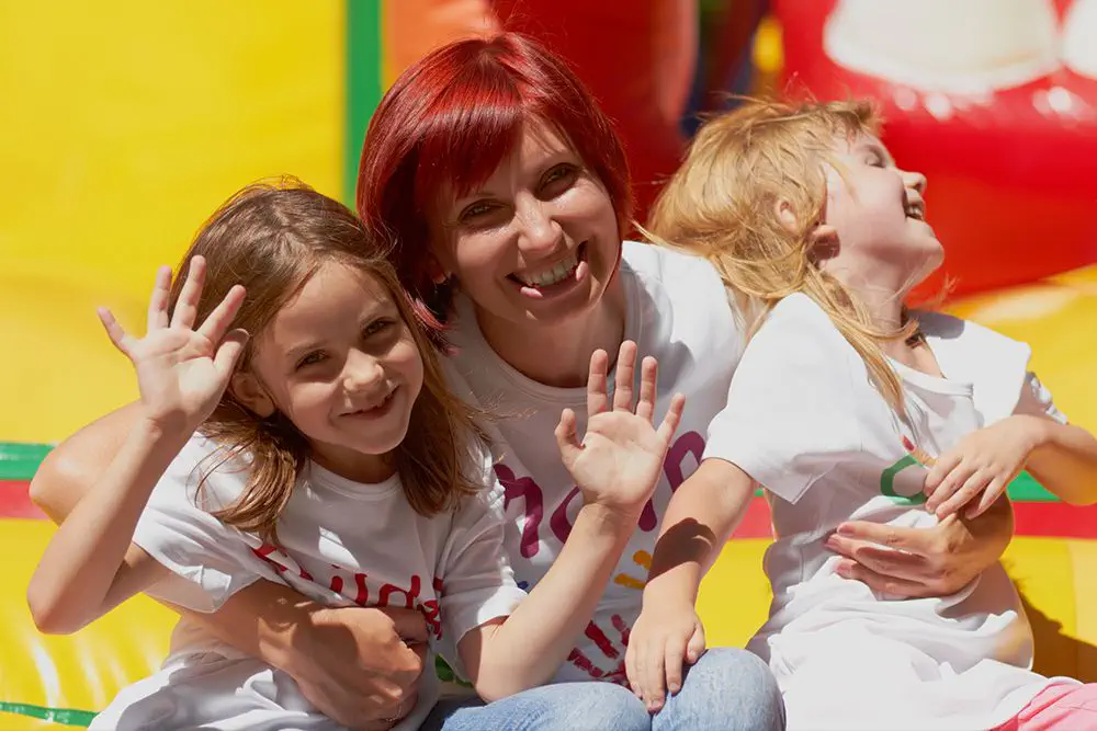 a very happy family on an inflatable bouncy castle at an outdoor summer event